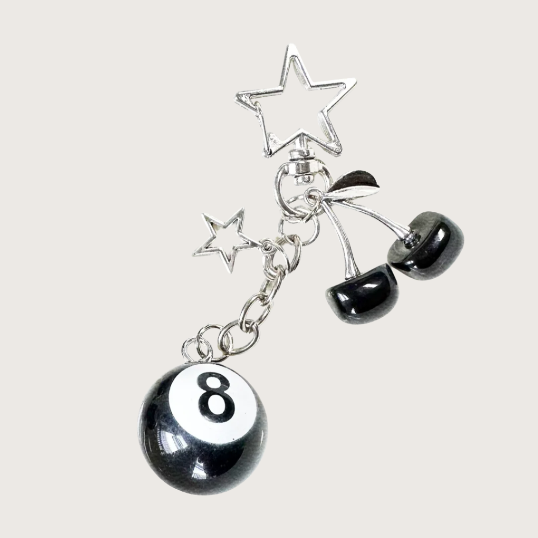 Keychain or bag charm with black and white 8-ball, star, and cherry charms on a white background